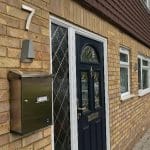 Serenissima Stainless Steel Wall Mounted External Post Box installed next to a blue front door