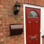 WA1 Wall Mounted External Post Box installed on a brick wall next to a red front door